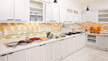 Kitchen area with a long countertop, white cabinetry, and geometric patterned backsplash.