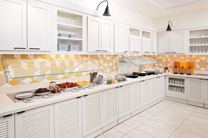 A modern kitchen with white cabinets, a glass-fronted buffet area, and a yellow and white geometric backsplash. - Hyatt Place New Orleans Convention Center (New Orleans)