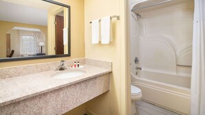 A bathroom with a granite countertop sink, a mirror, and a bathtub with a shower curtain. - Days Inn by Wyndham Thomaston (Thomaston)
