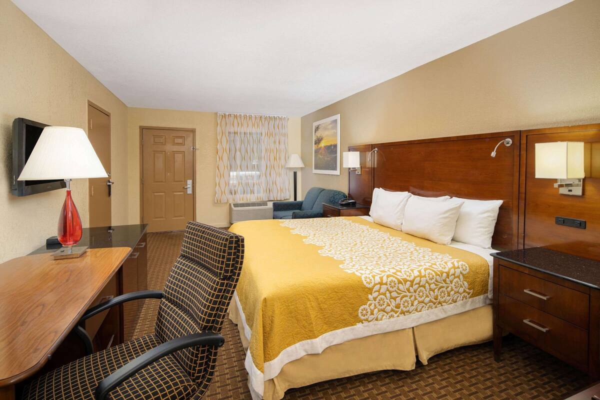 Ein Hotelzimmer mit Bett, Schreibtisch, Stuhl, Fernseher und Bad.