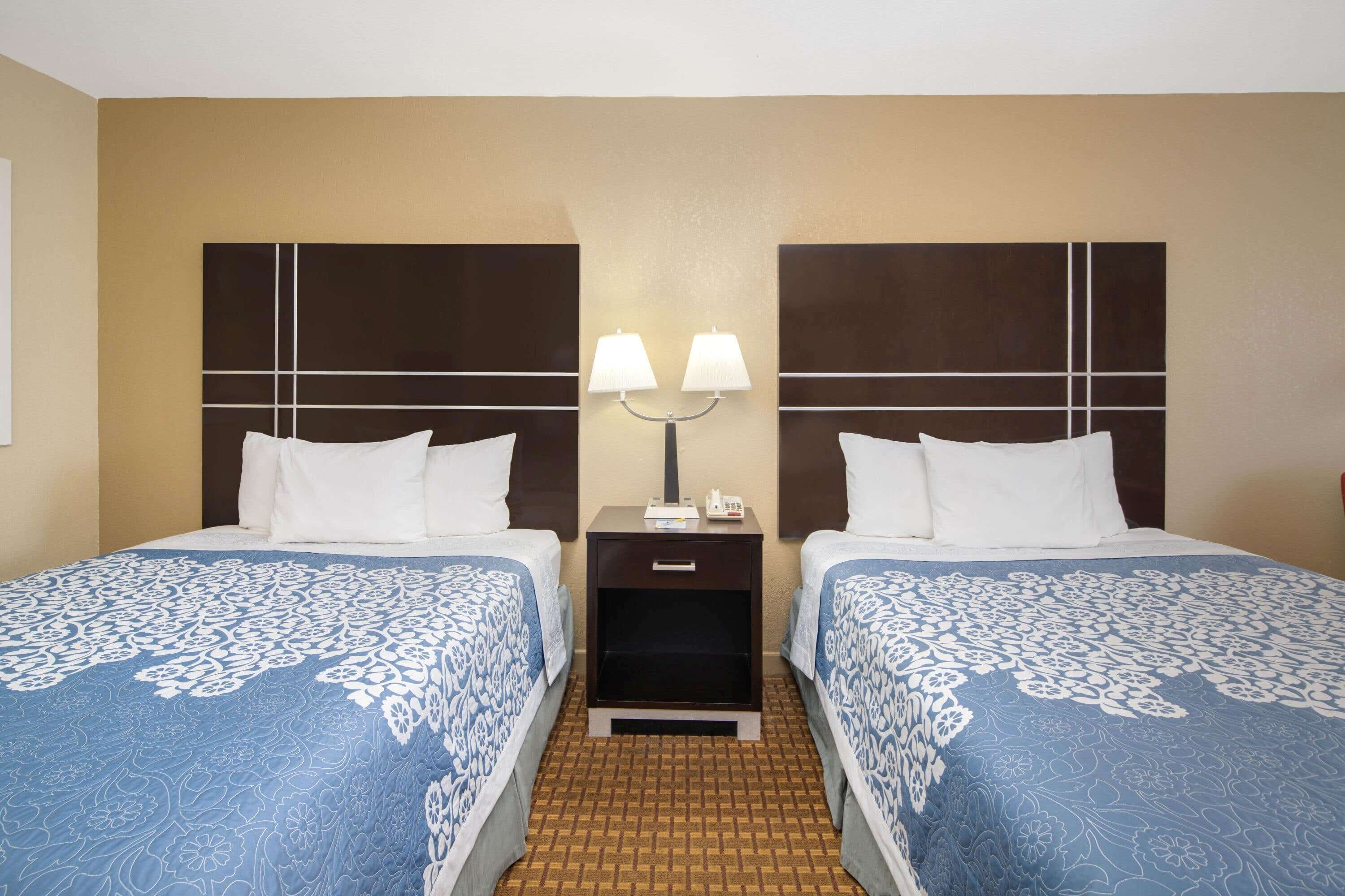 Une chambre d’hôtel avec deux lits, chacun doté d’une tête de lit et d’une table de chevet avec une lampe.
