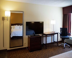 A hotel room with a bed, a television, a desk with a lamp, a chair, and a dresser. - Hampton Inn St. Louis/Chesterfield (Chesterfield)