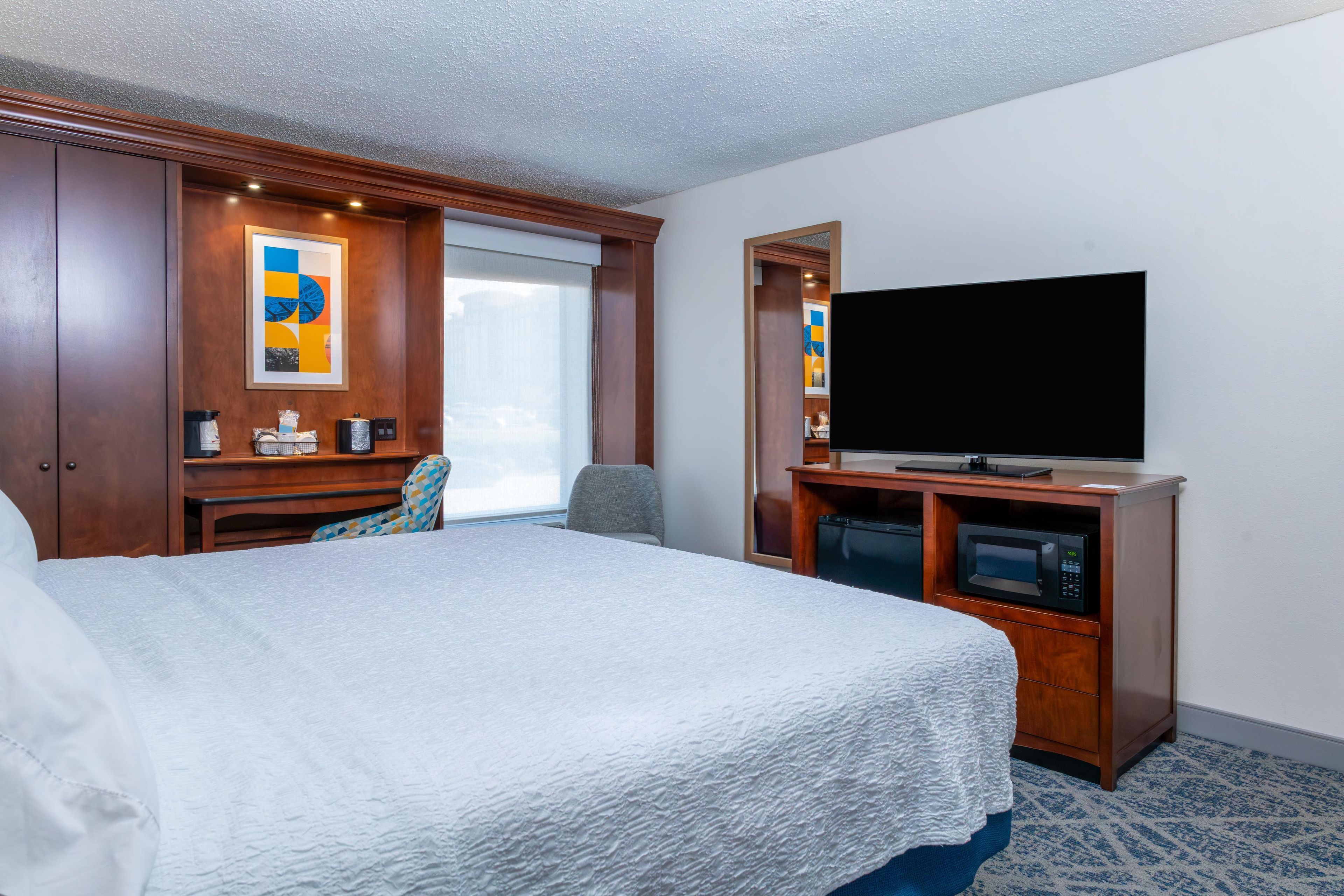 Habitación de hotel con una cama grande, un televisor de pantalla plana, un escritorio con una silla y una ventana.