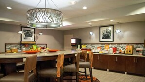 A modern kitchen with a central island, bar stools, and a patterned rug.