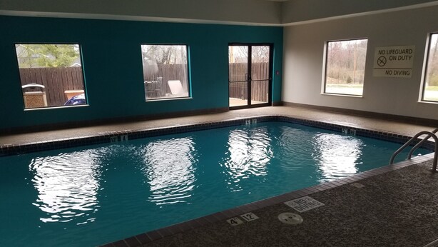 An indoor swimming pool with clear water, a tiled border, and a no diving sign.