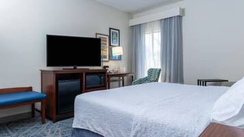 A hotel room with a bed, a television, a desk, a chair, and a microwave.