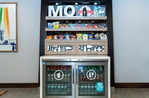 A vending machine with snacks and drinks, including Coca-Cola and Sprite, and a refrigerator below it. - Hampton Inn St. Louis/Chesterfield (Chesterfield)