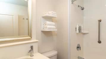 A bathroom with a sink, toilet, and shower. There are towels and toiletries on shelves.