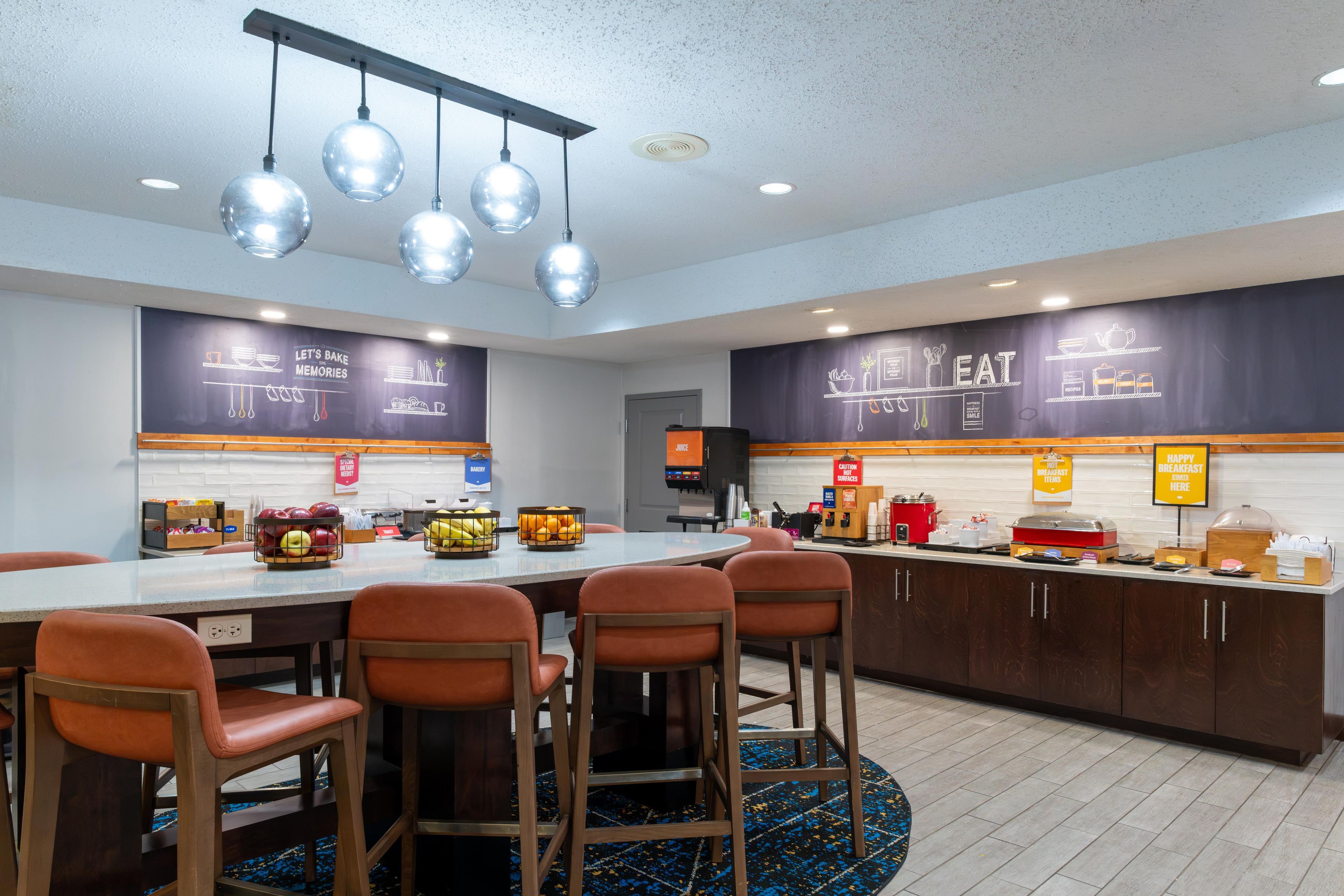 A modern kitchen area with a central island, bar stools, and a breakfast bar.