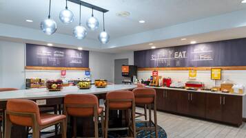 A modern kitchen area with a central island, bar stools, and a breakfast bar.