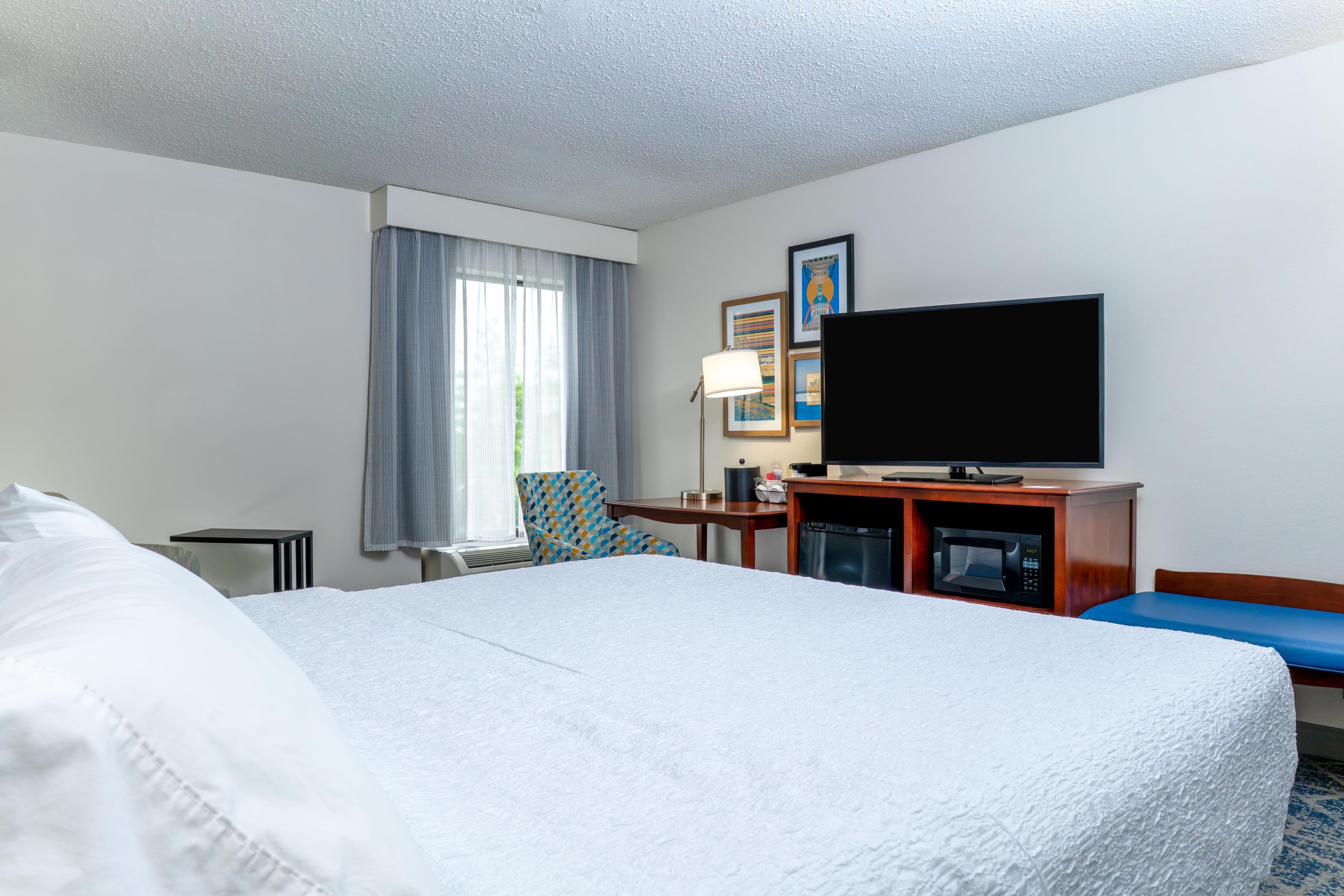 A hotel room with a bed, a television, a desk, and a chair.