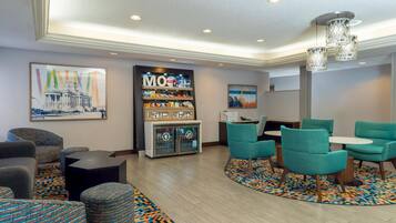 A modern lounge area with seating, a vending machine, and artwork on the walls.
