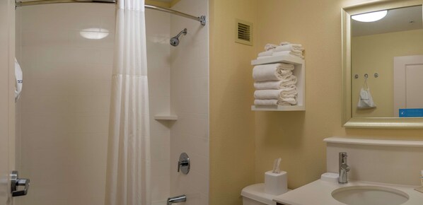 A bathroom with a shower, a toilet, a sink, and a towel rack with folded towels.