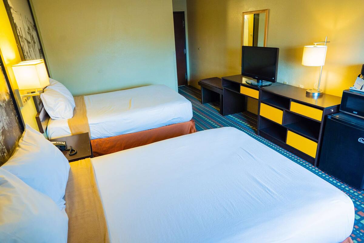 Ein Hotelzimmer mit zwei Betten, einem Schreibtisch, einem Fernseher und einer Minibar.