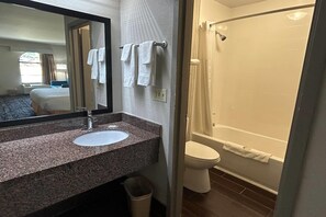 A bathroom with a sink, mirror, towel rack, toilet, and shower.