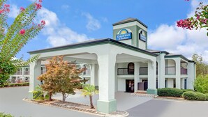 A Days Inn & Suites building with a central courtyard, a clock tower, and a sign indicating the hotel name. - Days Inn & Suites by Wyndham Stockbridge South Atlanta (Stockbridge)