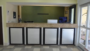 A reception area with a counter, a computer, and a green wall. - Eagles Nest Inn (Statesboro)