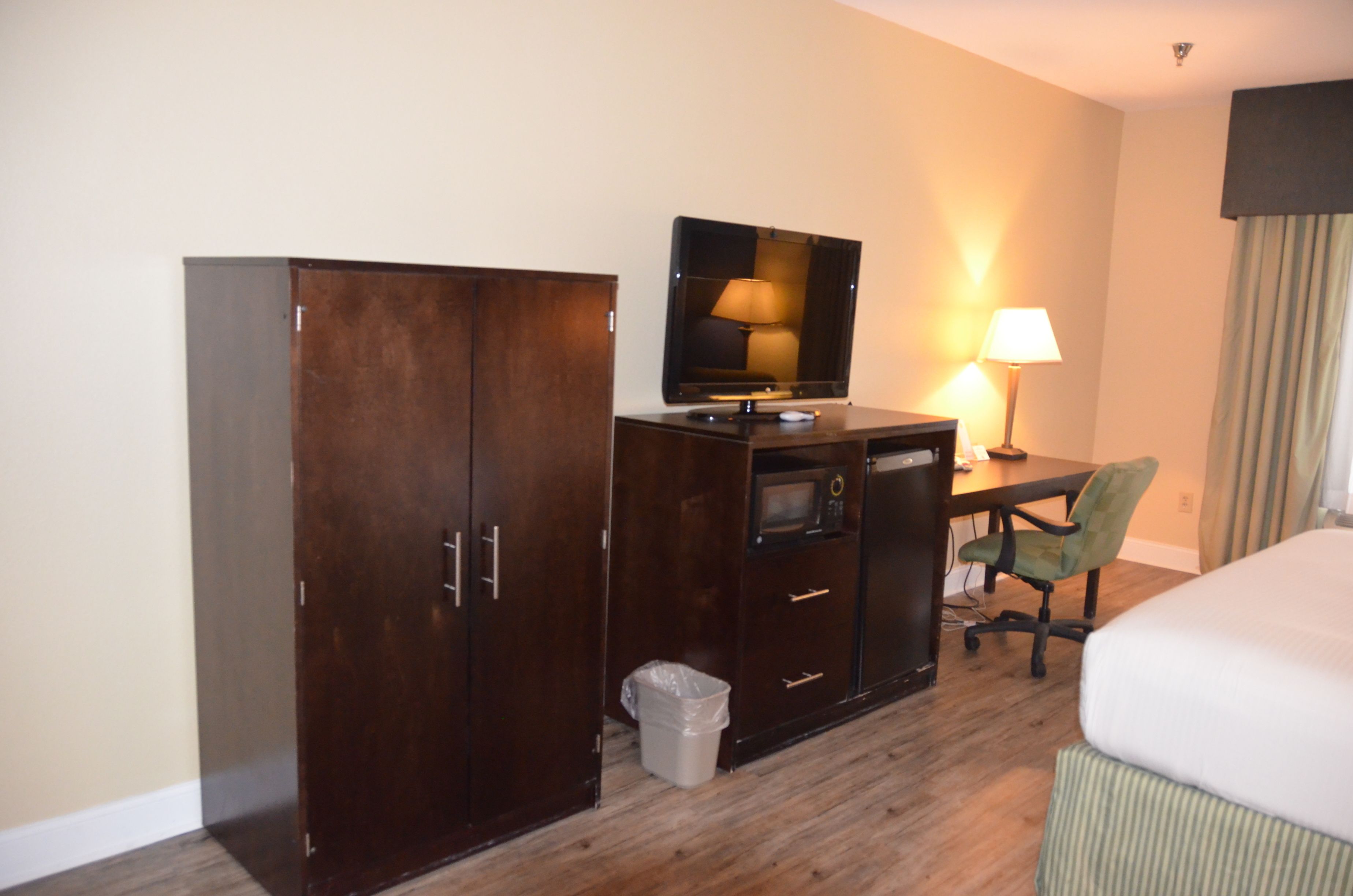 Ein Hotelzimmer mit Bett, Schreibtisch, Computer, Fernseher, Lampe und Papierkorb.