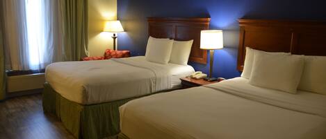 A hotel room with two beds, a nightstand with a lamp, a telephone, and a window with curtains.