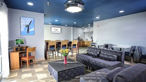 A modern lounge area with a sofa, chairs, a coffee table, and a desk with a computer. - Eagles Nest Inn (Statesboro)