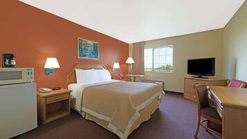A hotel room with a bed, bedside tables, a desk, a chair, a television, and a window.