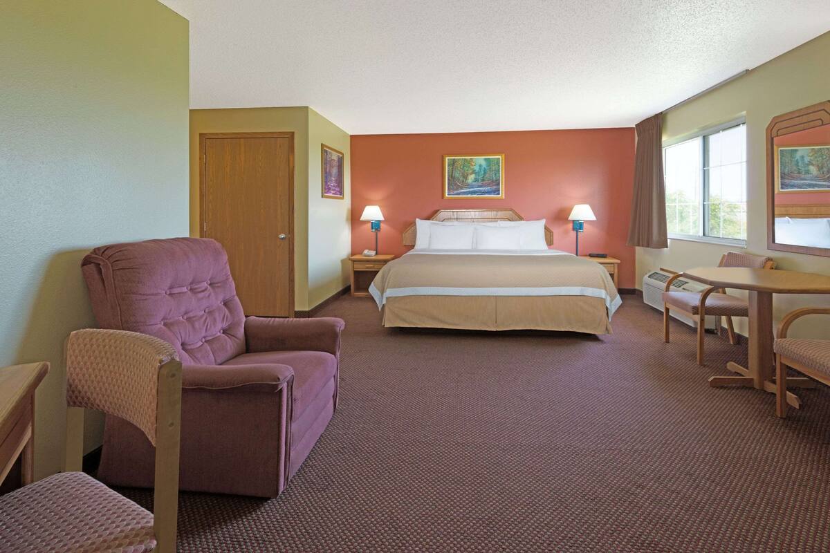 Ein Hotelzimmer mit Bett, Stuhl, Schreibtisch und Fenster.