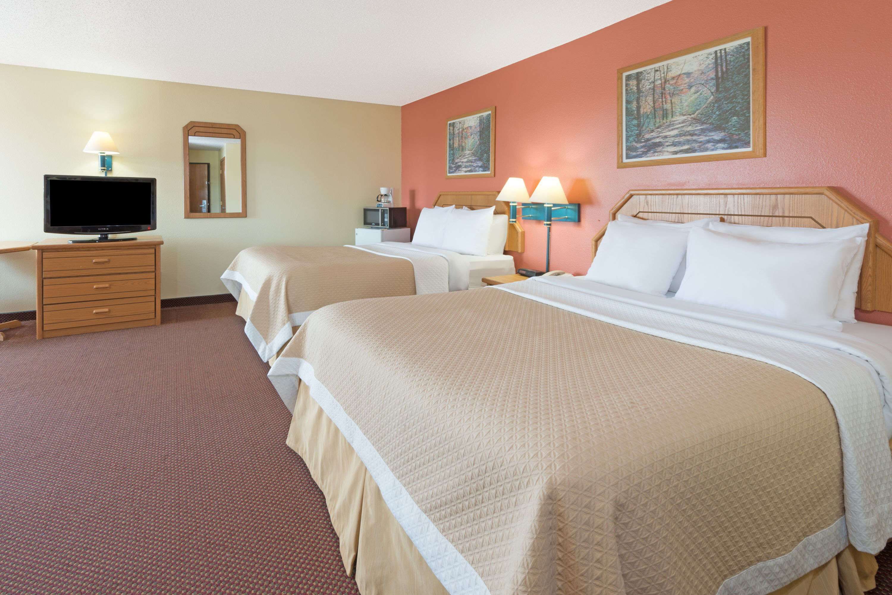 A hotel room with two beds, a television, a desk, and a coffee maker.