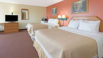 A hotel room with two beds, a television, a desk, and a coffee maker.