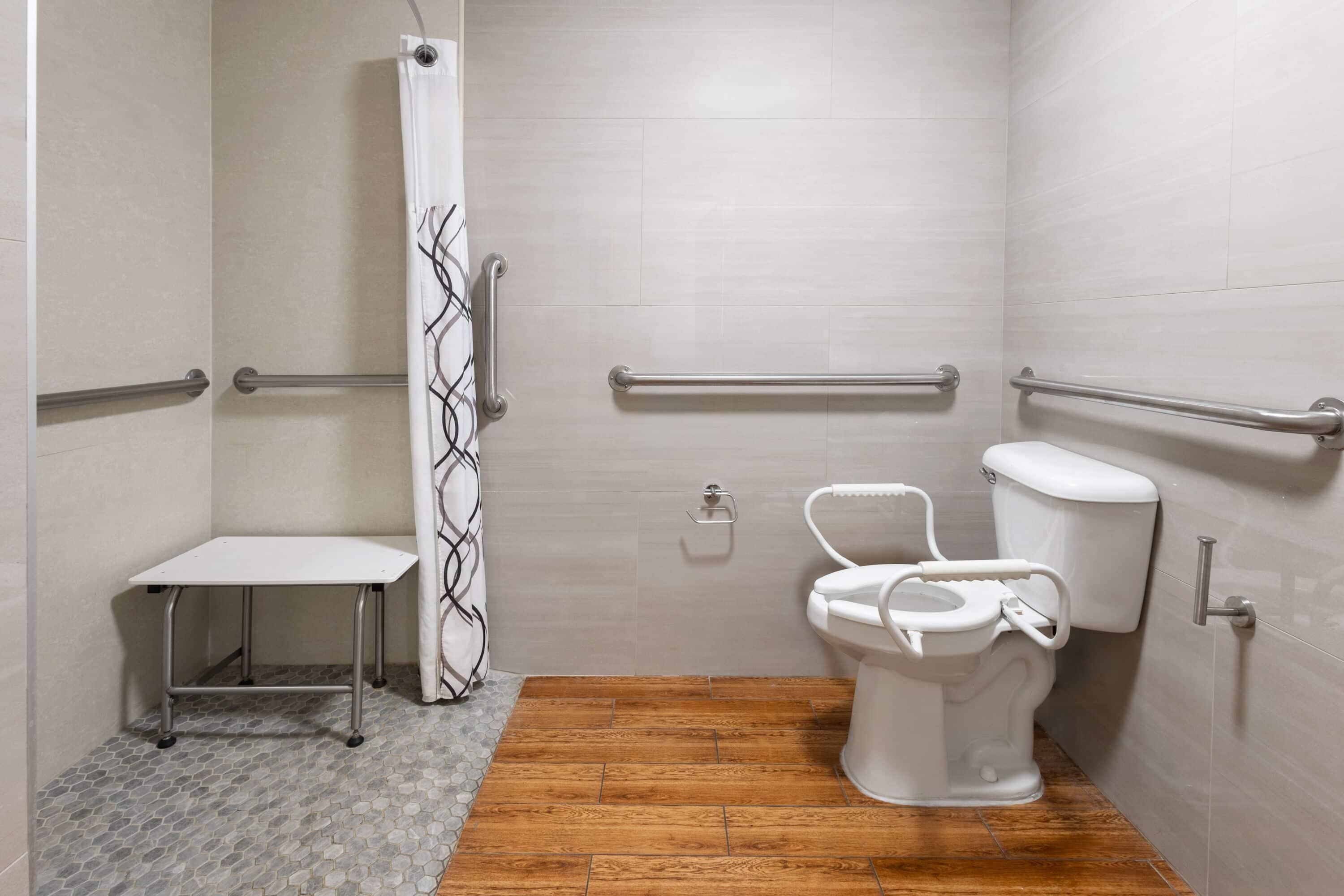 A bathroom with a shower, toilet, and a small table.