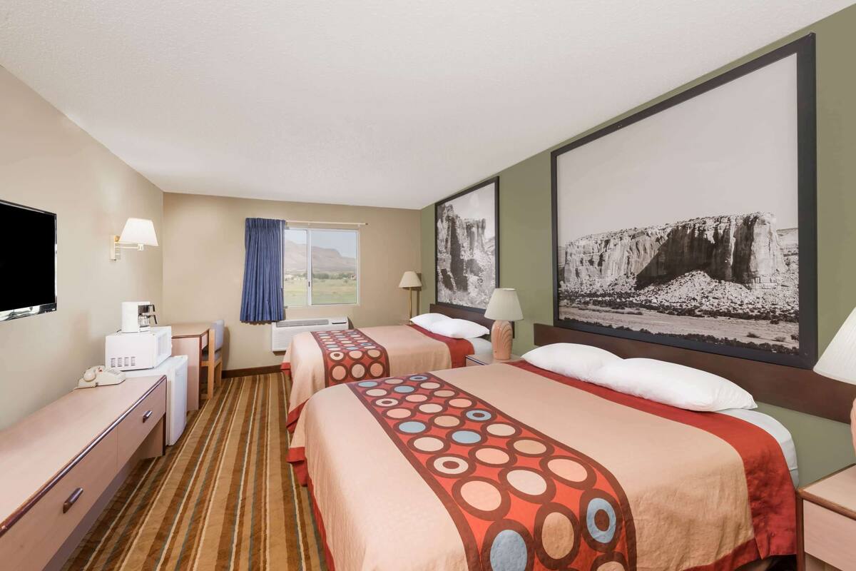Une chambre d’hôtel avec deux lits, un bureau, une télévision et une fenêtre donnant sur les montagnes.