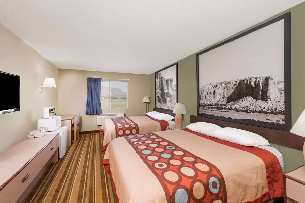 Une chambre d’hôtel avec deux lits, un bureau, une télévision et une fenêtre donnant sur un paysage agréable.