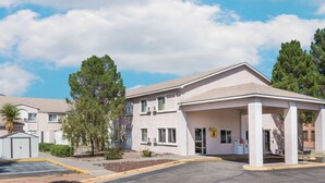 A single-story motel with a covered parking area, a FedEx pickup, and a sign indicating the motel's name.