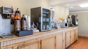 A self-service beverage station with coffee machines, a refrigerator, and a microwave.