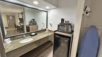 Casa de banho com lavatório, espelho, micro-ondas e porta-toalhas.