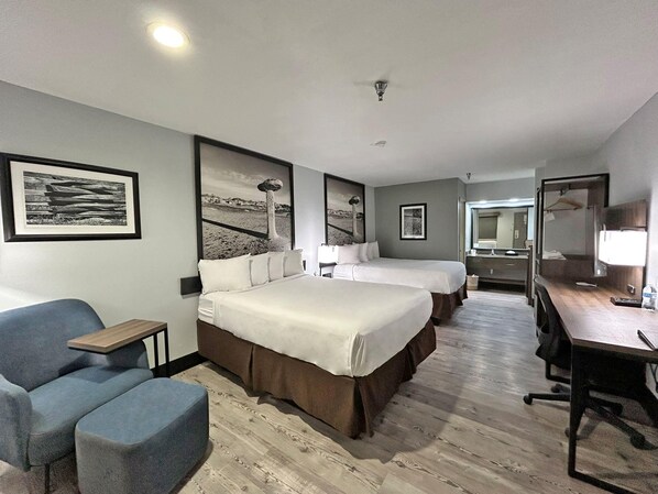 A hotel room with a large bed, a desk, a chair, and a mirror.