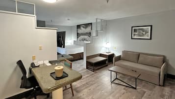 A compact hotel room with a kitchenette, a dining area, a sofa, and a bed.