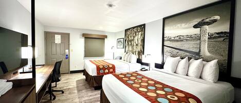 A hotel room with two beds, a desk, and a large window.