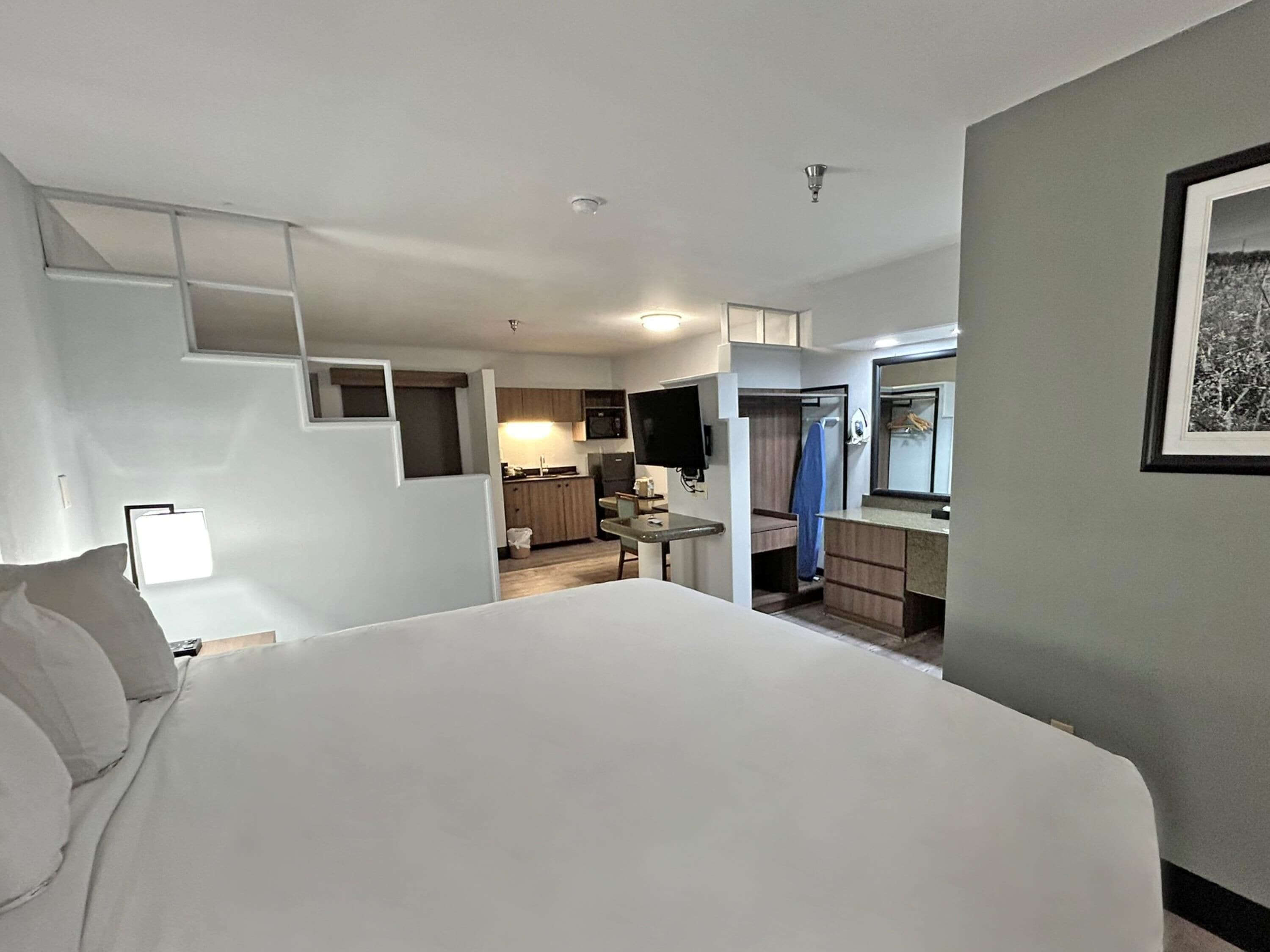 Ein Hotelzimmer mit Bett, Schreibtisch, Küchenzeile und Bad.