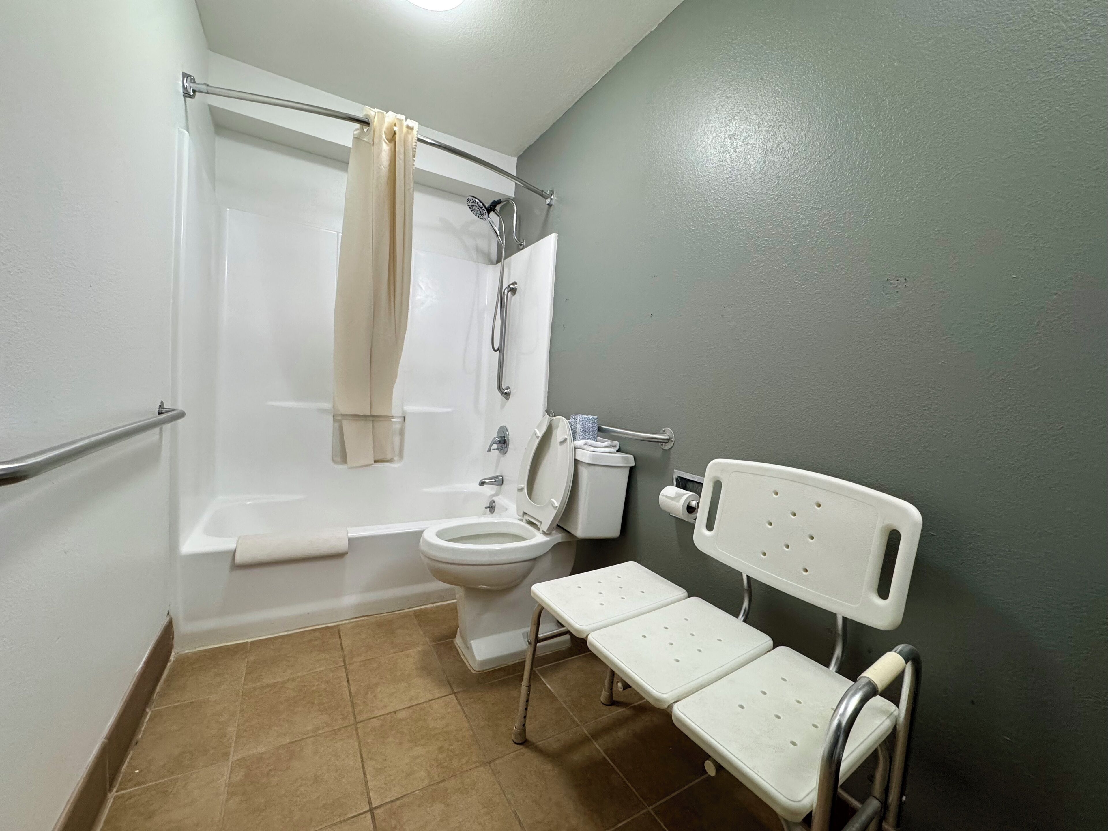 A bathroom with a bathtub, toilet, and a bench.