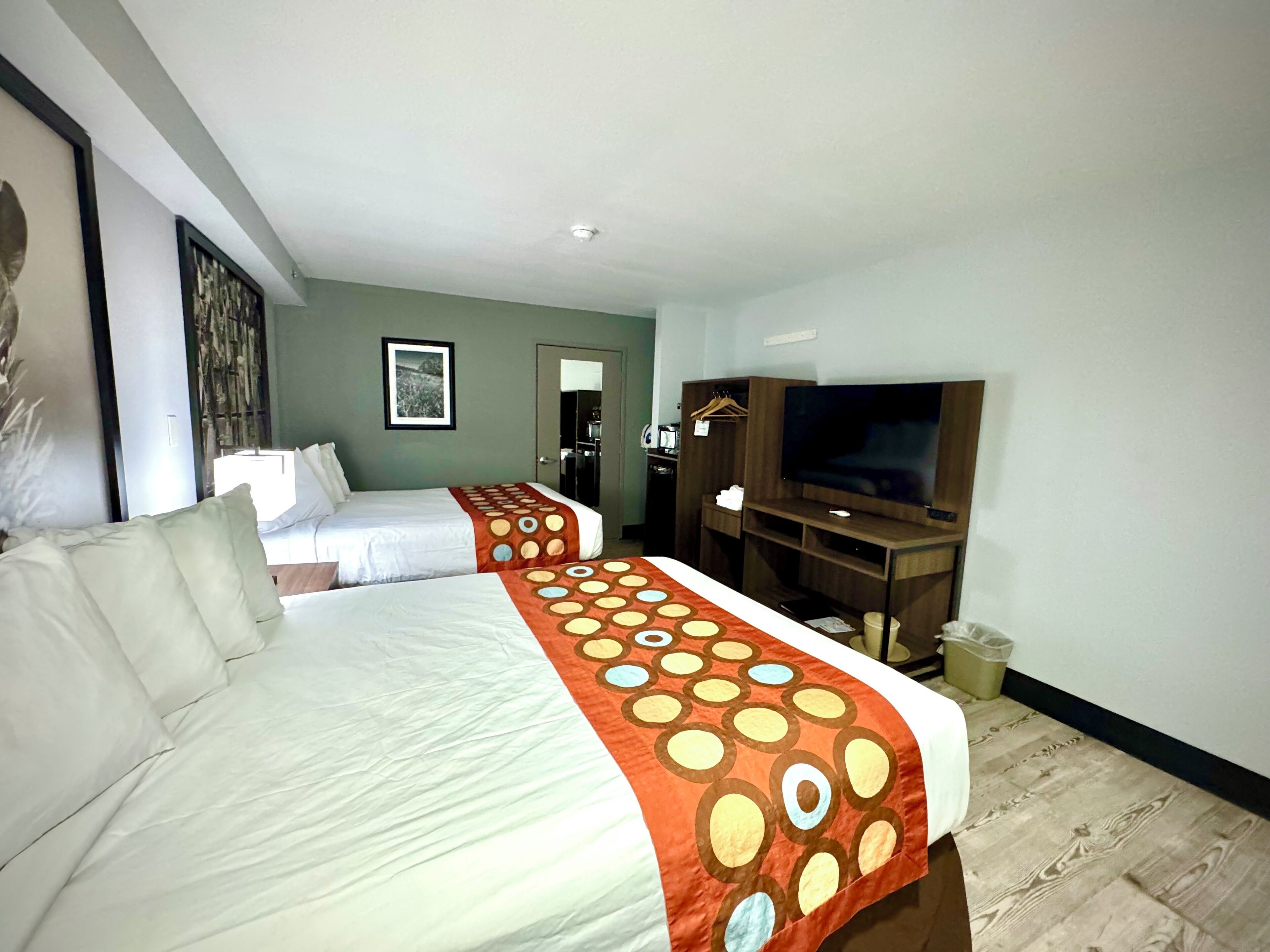 Habitación de hotel con dos camas, televisión y espejo.