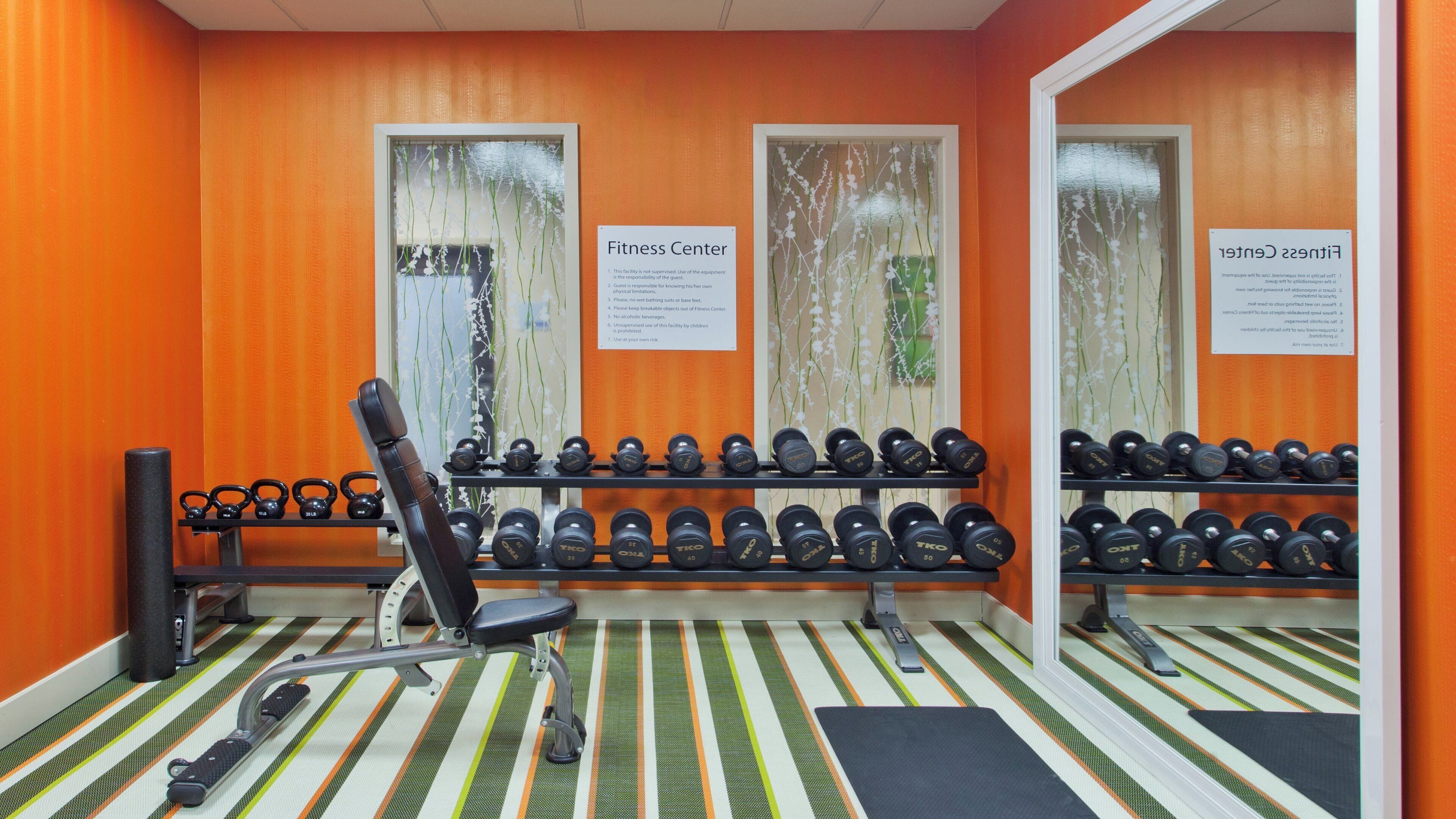 A fitness center with exercise equipment, including dumbbells and a bench.