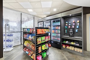 A self-service beverage and snack area with refrigerated drinks and a variety of packaged snacks. - Holiday Inn Express Atlanta Galleria - Ballpark Area by IHG (Atlanta)