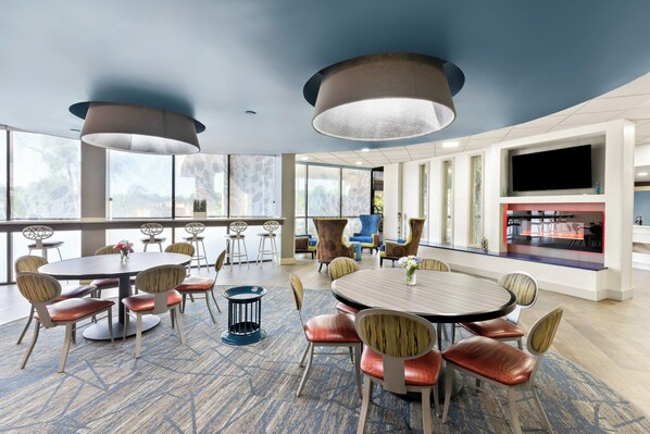 A spacious conference room with round tables and chairs, large windows, and a flat-screen TV. - Holiday Inn Express Atlanta Galleria - Ballpark Area by IHG (Atlanta)