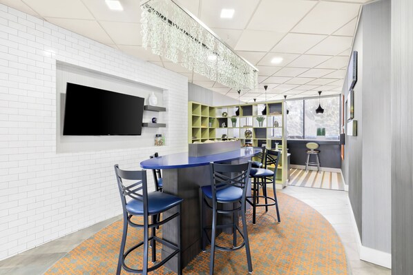 Een moderne bar met een flatscreen televisie, barstoelen en een kamerbreed tapijt.