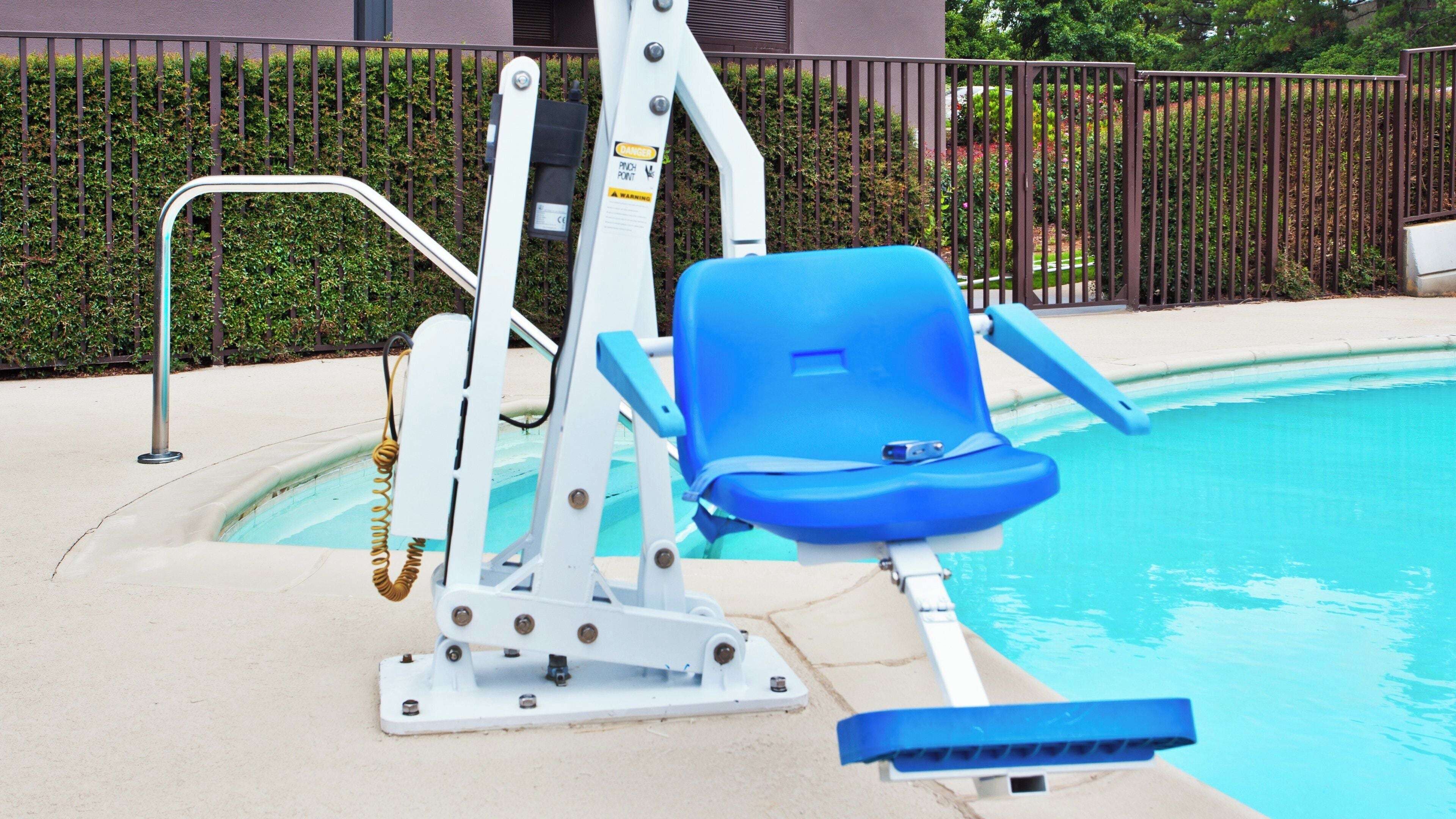 Uma área da piscina com uma espreguiçadeira azul, barra de segurança e elevador para piscina.
