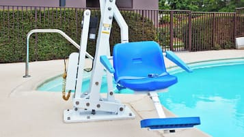 Uma área da piscina com uma espreguiçadeira azul, barra de segurança e elevador para piscina.