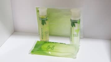 A set of toiletries including a shampoo bottle, a body wash, and a face wash, all in green packaging with a leaf design.