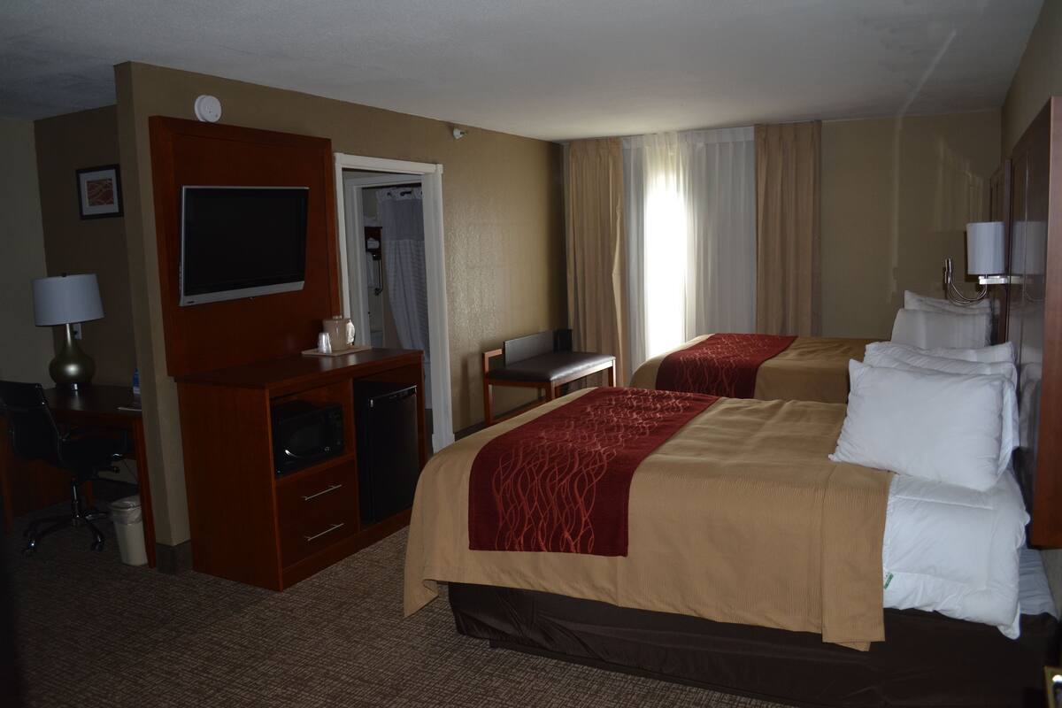 A hotel room with a bed, desk, chair, and a television.