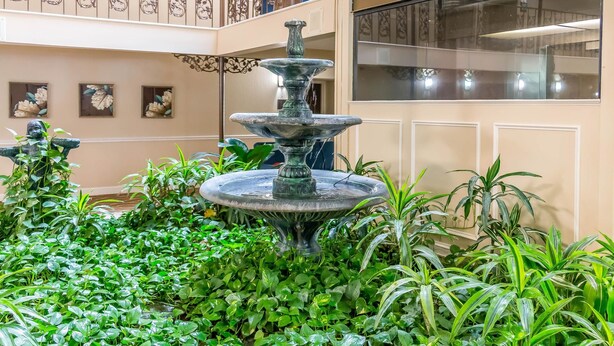 A multi-level atrium with a central fountain surrounded by lush greenery, framed by decorative wall panels and artwork. - Comfort Inn Savannah Midtown (Savannah)
