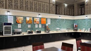 A modern kitchen area with a buffet setup, including a coffee machine, a microwave, and various food display items. - Comfort Inn Savannah Midtown (Savannah)